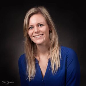 zakelijk kleuren portret van jonge onderwijzeres tegen donkere achtergrond