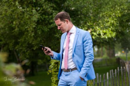 zakelijk portret van jonge succesvolle man gefotografeerd op buitenlocatie kijkend op zijn smartphone