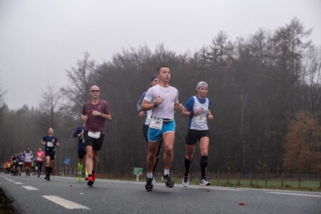 evenementfotografie Montferlandrun renners lopen in regenachtig weer over verharde weg