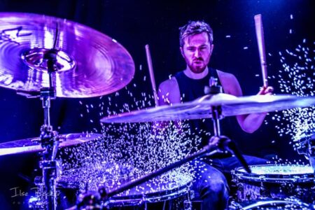 portret van drummer waarbij tijdens het drummen de rijst van zijn drumstel spat