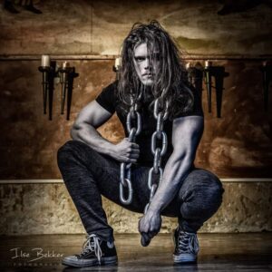 portretfotografie zeer sterk beeld van jonge gespierde sporter met zware ketting bijzondere manier van fitness in het voormalig juvenaat zevenaar