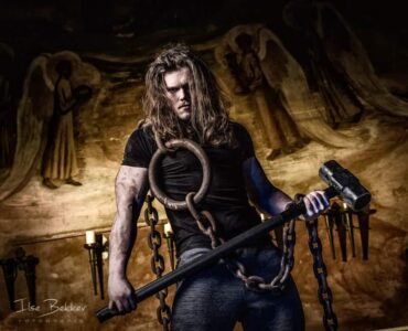 portretfotografie jonge gespierde sporter met zware hamer en grote ketting bijzondere manier van fitness in het voormalig juvenaat zevenaar