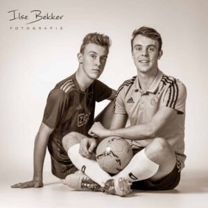 Foto van twee broers zittend naast elkaar in voetbal tenue 10 jaar later