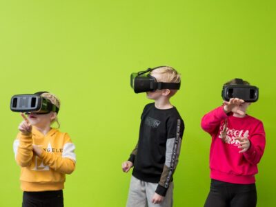 afbeelding van drie kinderen die een virtuality bril dragen tegen een felgroene achterwand