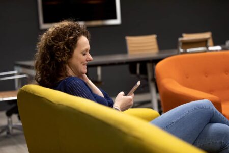 foto van zakenvrouw met telefoon op gele bank